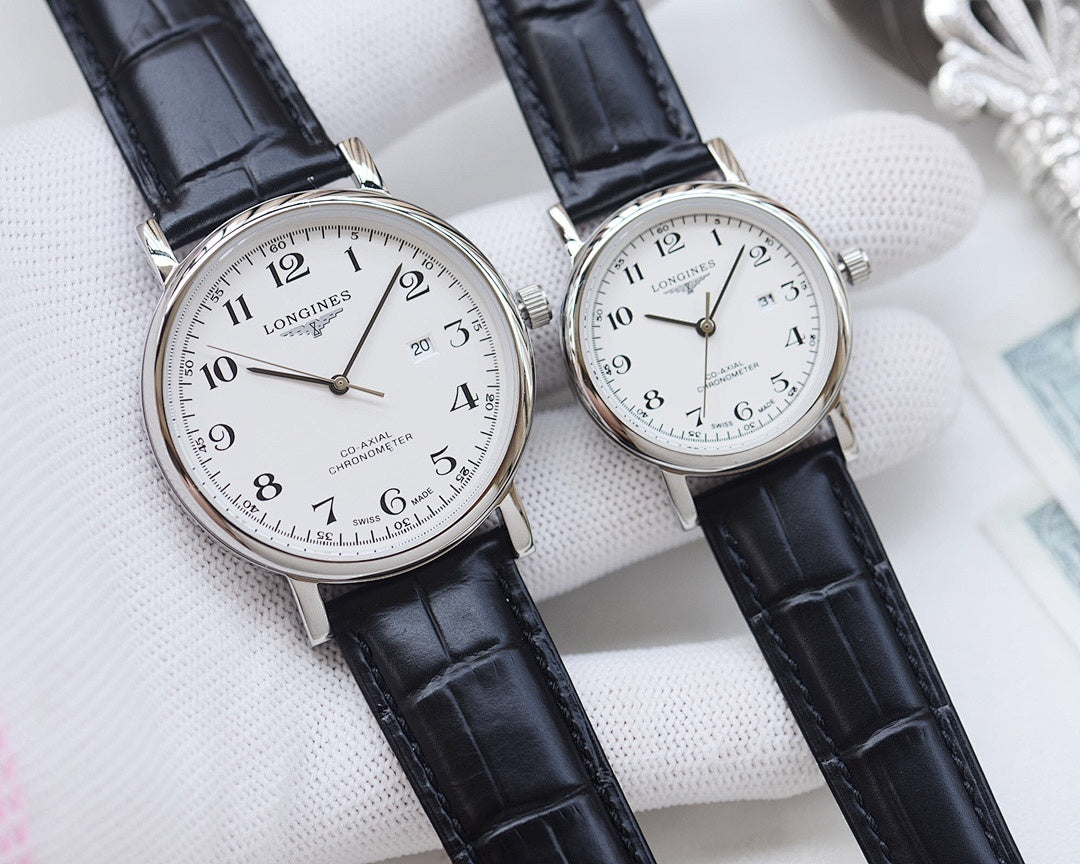 Longines watch pair with white dials, silver cases, and black leather straps on white pillow