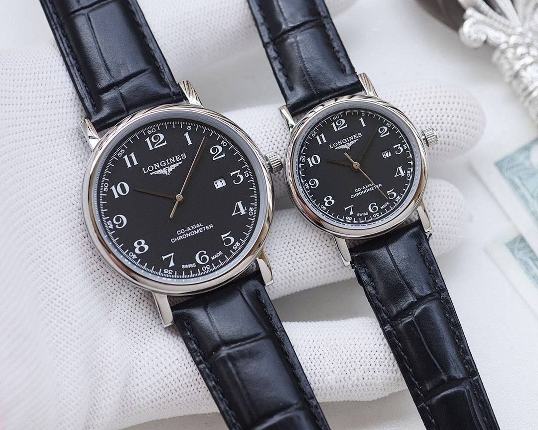 Longines watch pair with dark dials, stainless-steel cases, and black leather straps on pillow