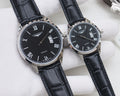 Black dial quartz watch with Roman numerals, date window, black leather strap, silver case