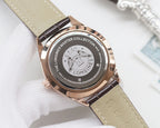 Rose gold watch case back with engraved emblem, beige leather strap, metal crown