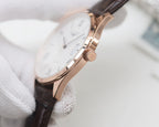 White dial quartz watch with rose gold case, Roman numerals, dark leather strap