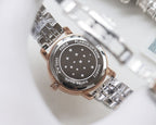 Longines wristwatch caseback with engraved star pattern and steel bracelet