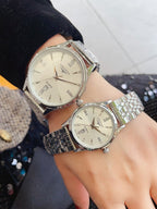Longines watch set on wrists with silver metal bands and light cream dials