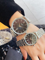Longines watches on wrists with silver metal bands and dark brown round dials