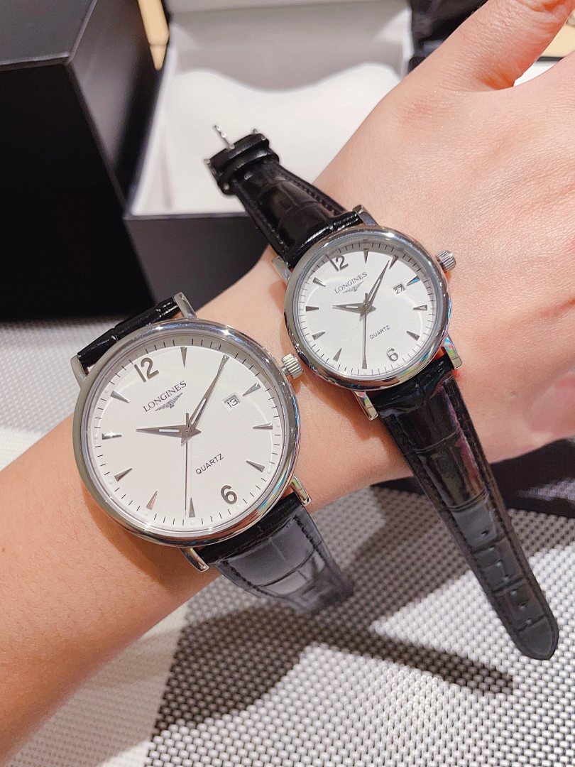 Leather-banded watch with white dial, black strap; round silver-tone case.