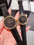Leather-banded watch with dark dial, brown strap; round gold-tone cases.