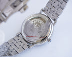Longines wristwatch caseback with engraved emblem and stainless steel bracelet links