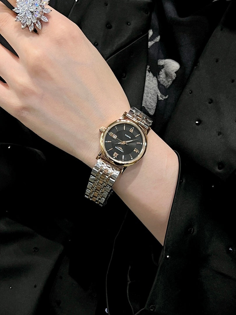 Round wristwatch with dark dial and silver metal link bracelet on a wrist