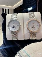 Dual Longines wristwatches on a display pillow, silver and rose-gold tone metal bracelets
