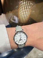 Longines wristwatch on a wrist, light-colored leather strap and white dial with moon-phase