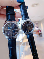 Two Longines wristwatches with dark blue leather straps and dark dials, held up