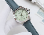 Round wristwatch with light green dial and blue leather strap, silver bezel