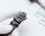 Analog watch with brown leather strap and silver clasp, side view