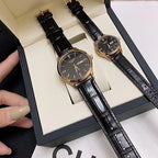 Longines watch with dark dial and black leather strap, shown in hand over box.