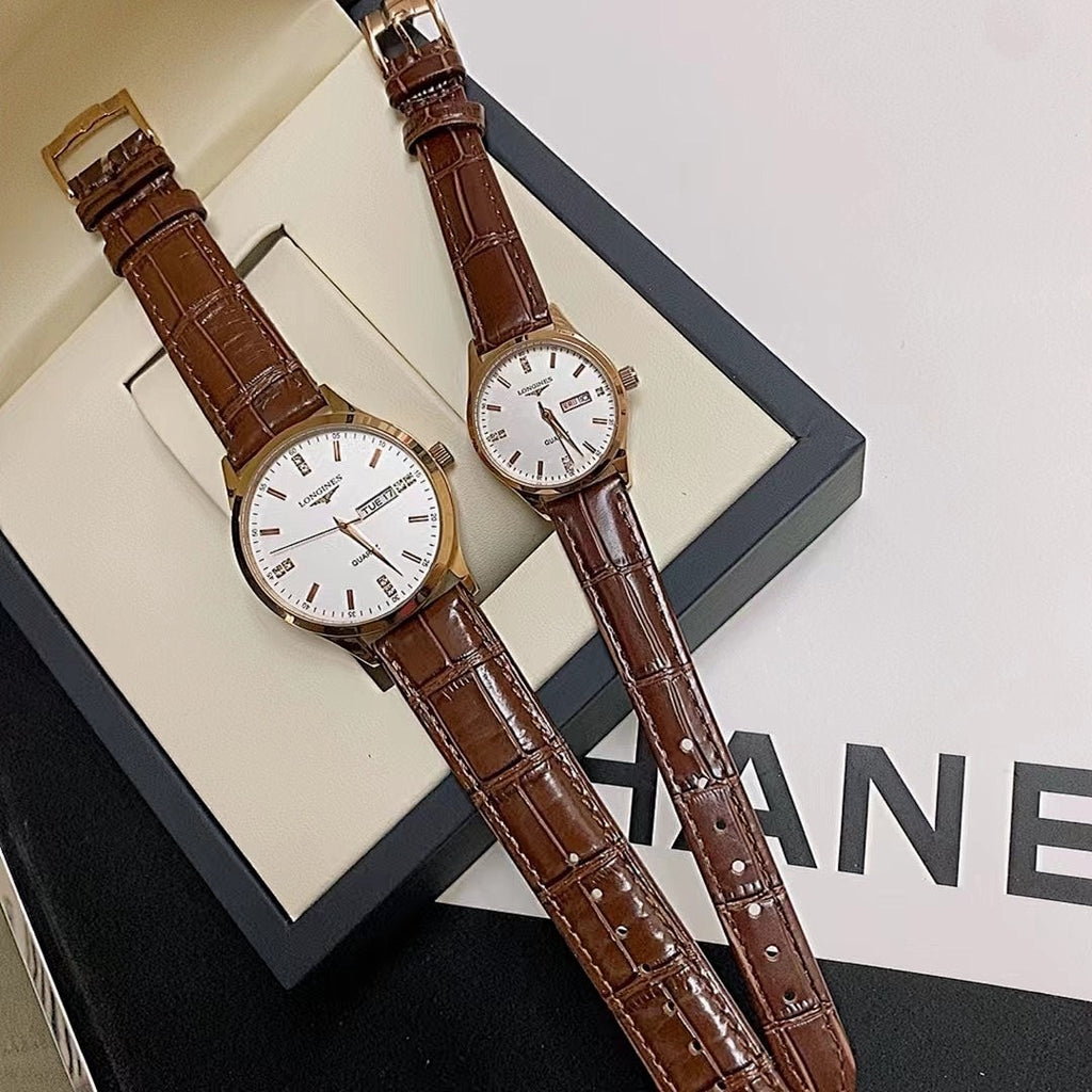 Longines watch pair with white dials and brown leather straps, laid in box.
