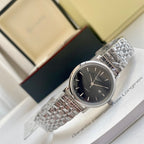 Longines watch with dark dial and silver metal link bracelet on display.