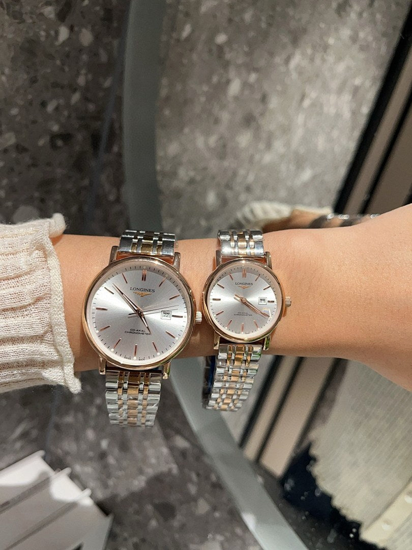 Two Longines watches with white dials and gold-tone metal bracelets on wrist.