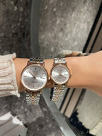 Two Longines watches with white dials and gold-tone metal bracelets on wrist.