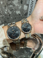 Two Longines watches with black dials and gold-tone metal link bracelets on wrist.