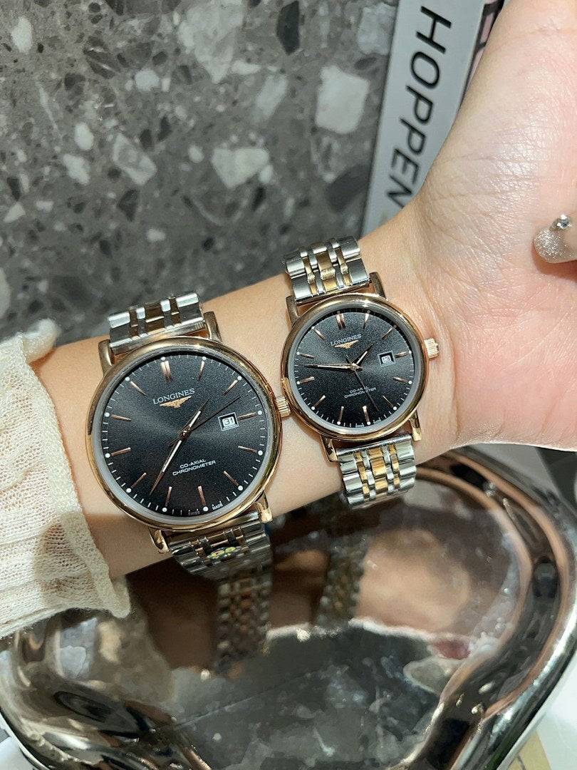 Two Longines watches with black dials and gold-tone metal link bracelets on wrist.