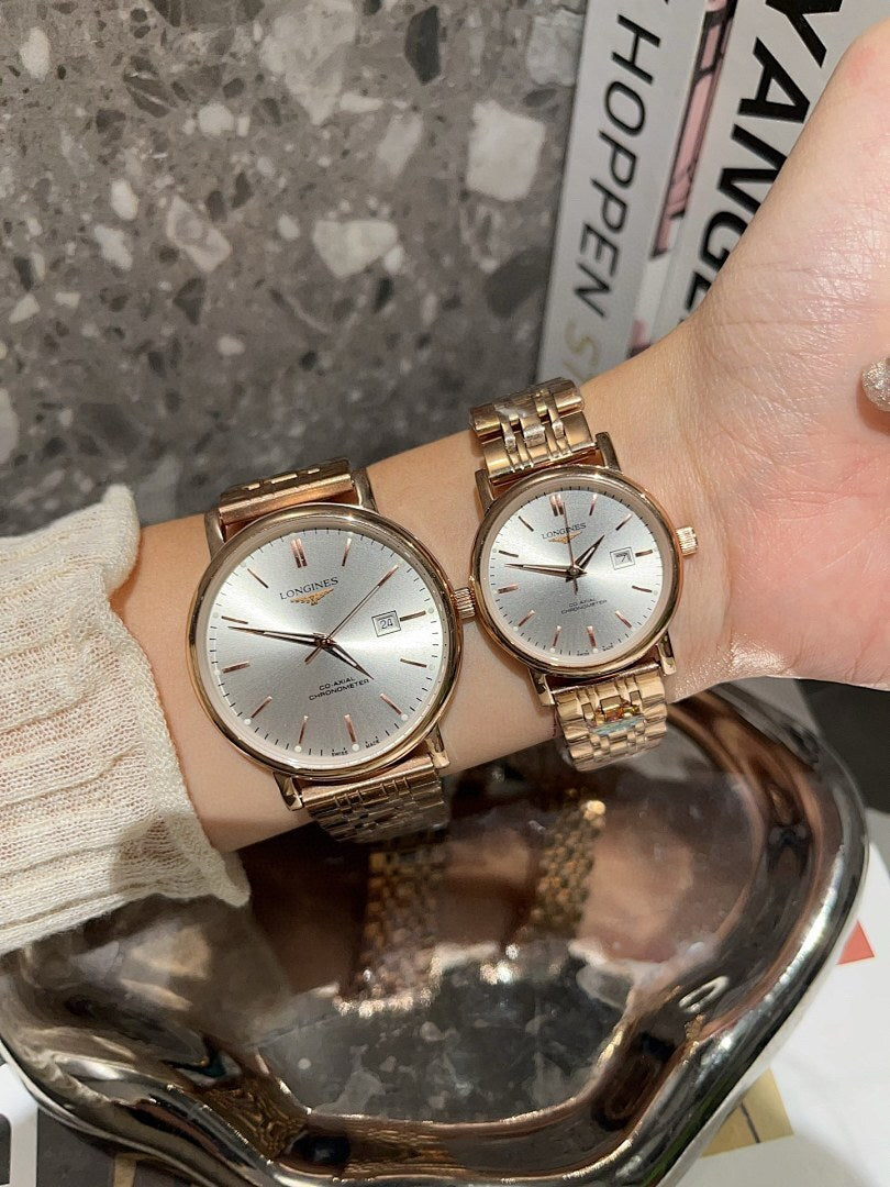 Two Longines watches with white dials and rose-gold metal link bracelets on wrist.