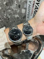 Two Longines watches with black dials and silver-toned metal link bracelets on wrist.