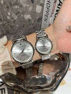 Two Longines watches with white dials and silver-toned metal link bracelets on wrist.