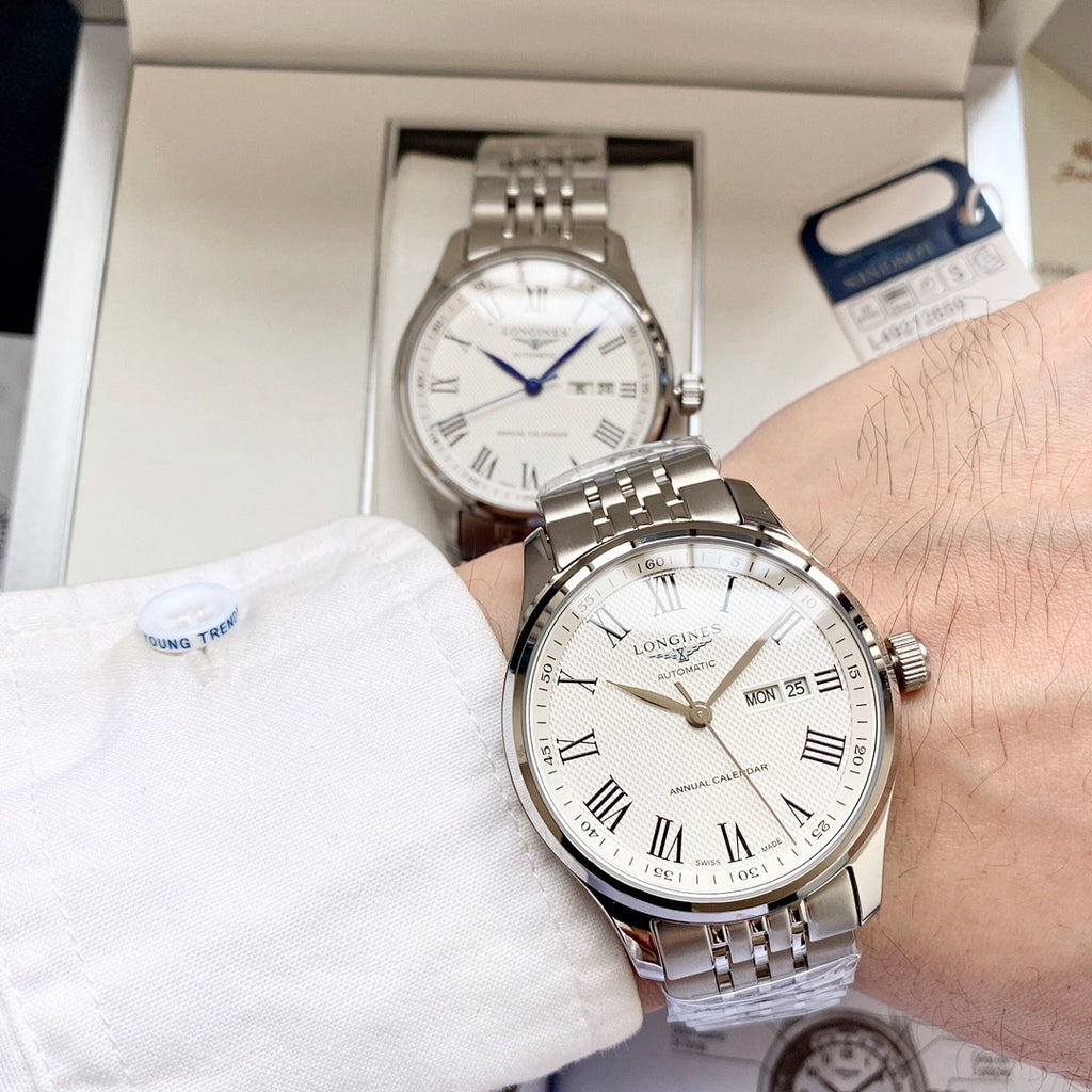 Longines watch with white dial and steel bracelet on wrist, date MON 25