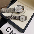 Stainless steel wrist watches with white dials and link bracelets on a gift tray