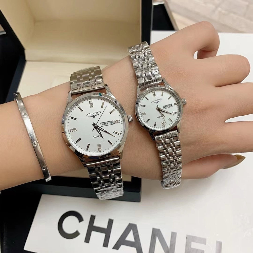 Two stainless steel wrist watches with white dials on a display box surface