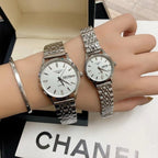 Two stainless steel wrist watches with white dials on a display box surface