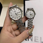 Stainless steel wrist watches with white dials and round cases held in a hand