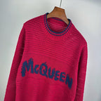Magenta knit sweater close-up with blue McQueen logo band and ribbed collar