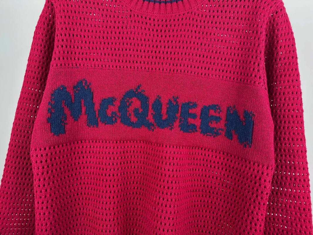Magenta knit sweater close-up with large blue McQueen logo across the chest