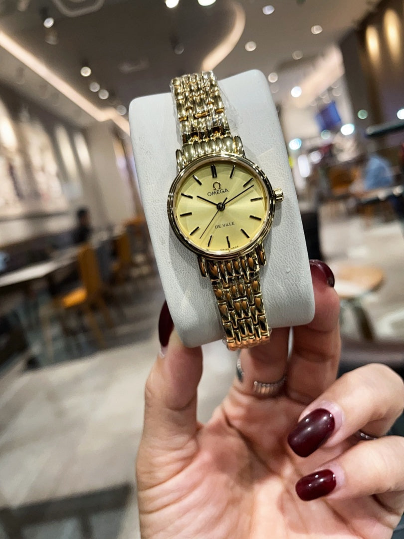 Omega wristwatch with gold-tone link bracelet and champagne dial on display cushion