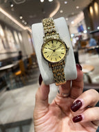 Omega wristwatch with gold-tone link bracelet and champagne dial on display cushion
