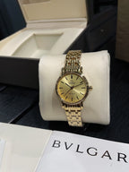 Omega wristwatch with gold-tone bracelet and champagne dial on a white display stand