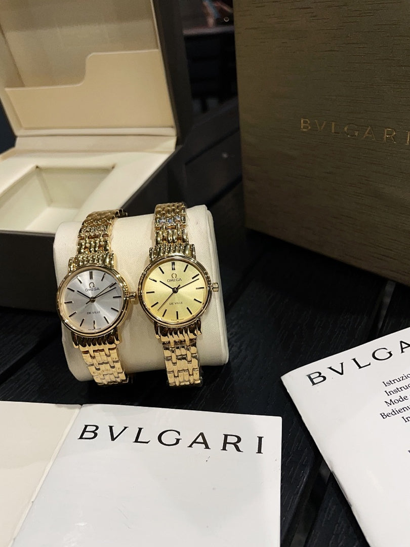 Pair of Omega wristwatches with gold-tone link bracelets and champagne and white dials