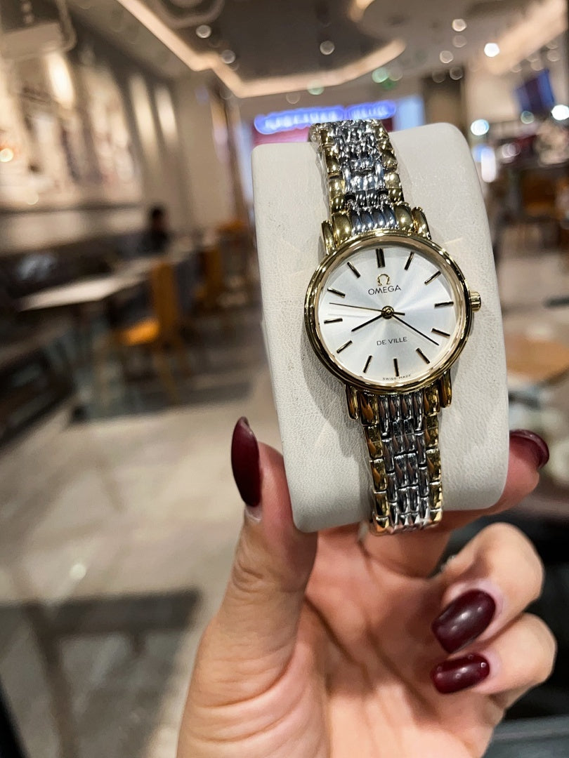 Omega wristwatch with white dial and linked metal bracelet held upright