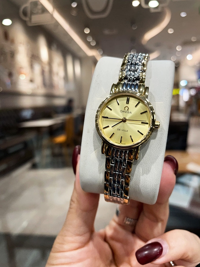 Omega wristwatch with gold dial and linked metal bracelet in front view