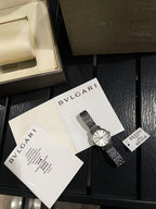 Omega De Ville wristwatch with silver metal bracelet, shown with papers