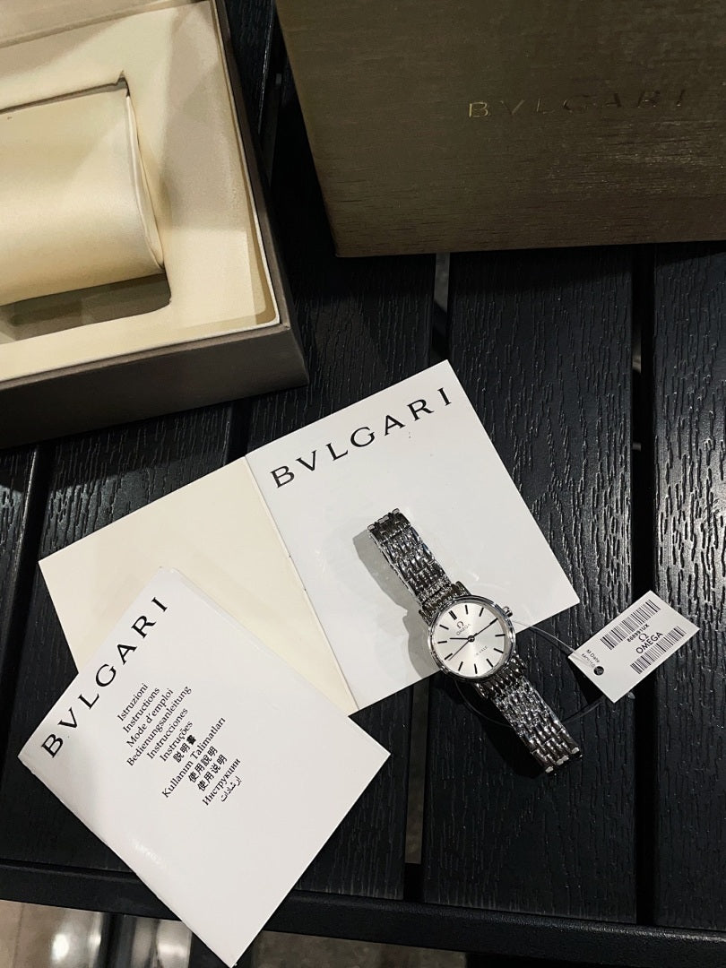 Omega De Ville wristwatch with silver metal bracelet, shown with papers