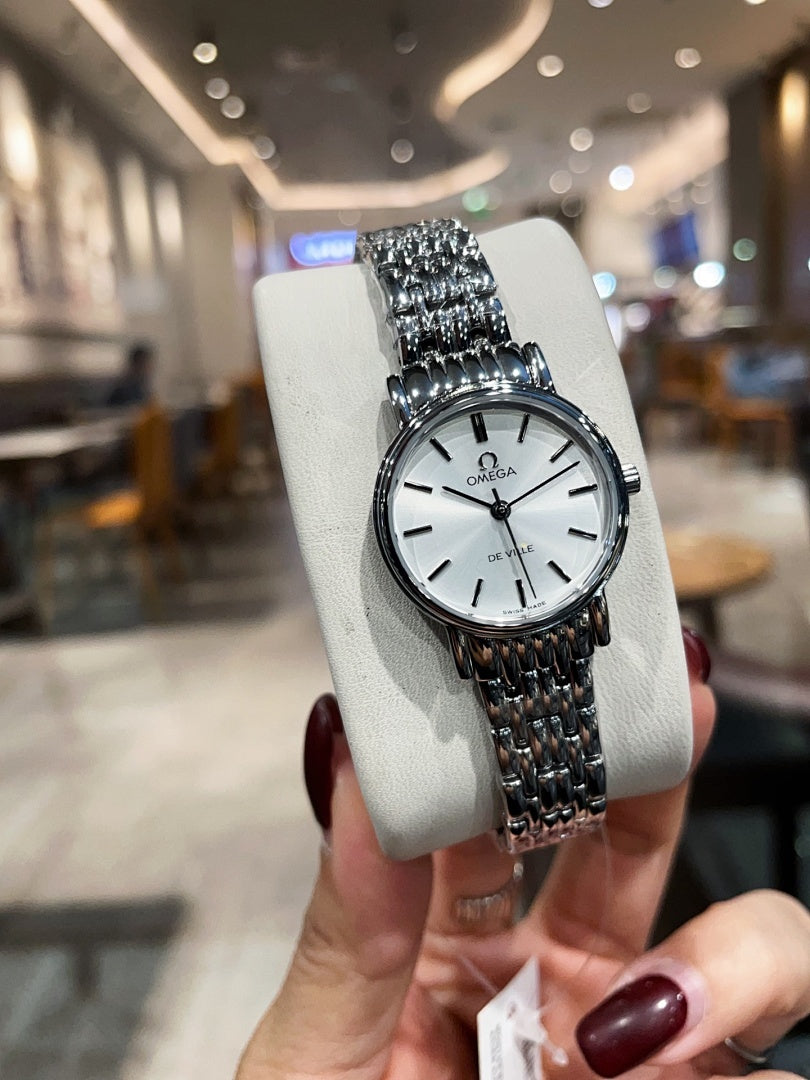 Omega De Ville wristwatch on gray cushion, silver-tone bracelet and white dial