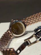 Omega watch case back with engraved branding and brown patterned strap