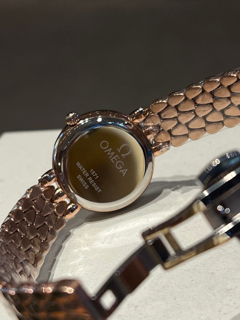 Omega watch case back with engraved branding and brown patterned strap