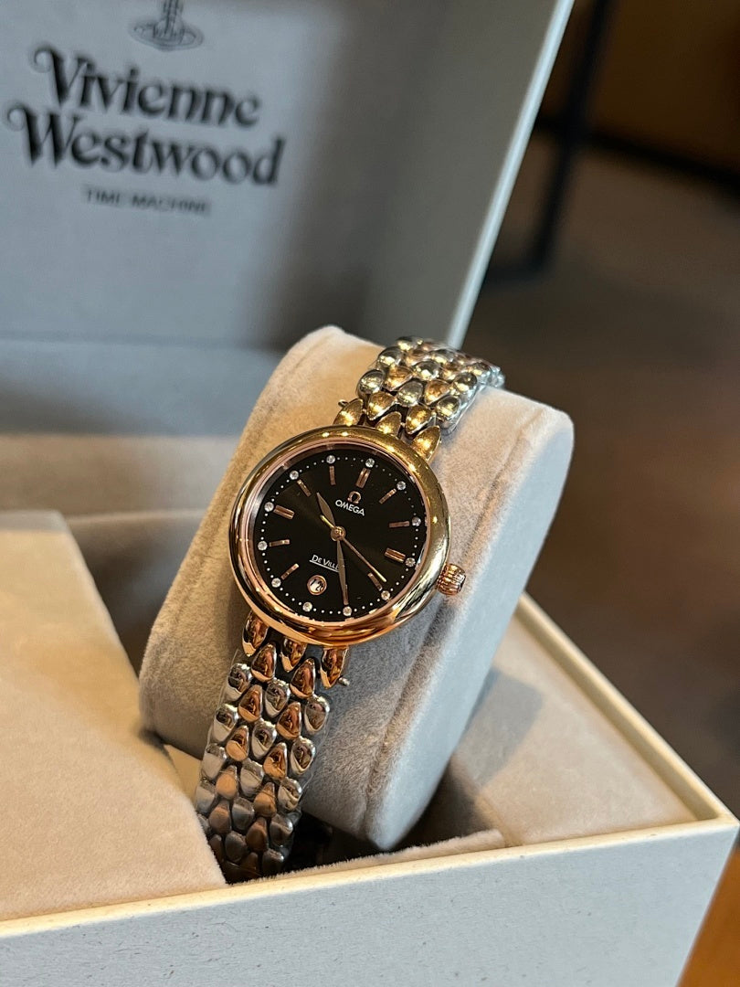 Gold-tone Omega wristwatch with black dial, gem-set bezel, and link bracelet