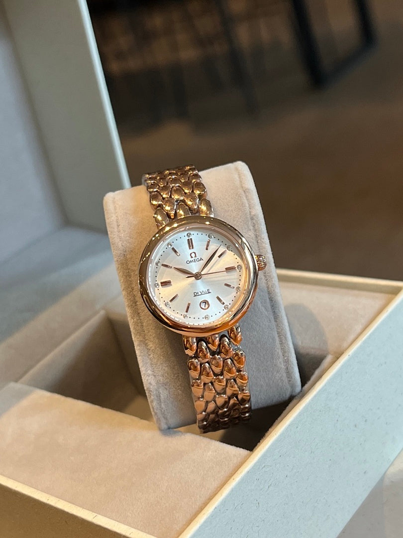 Gold-tone Omega wristwatch with white dial, gem-set bezel, and link bracelet