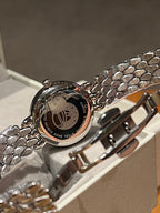 Omega wristwatch caseback close-up with engraved metal design, textured bracelet links