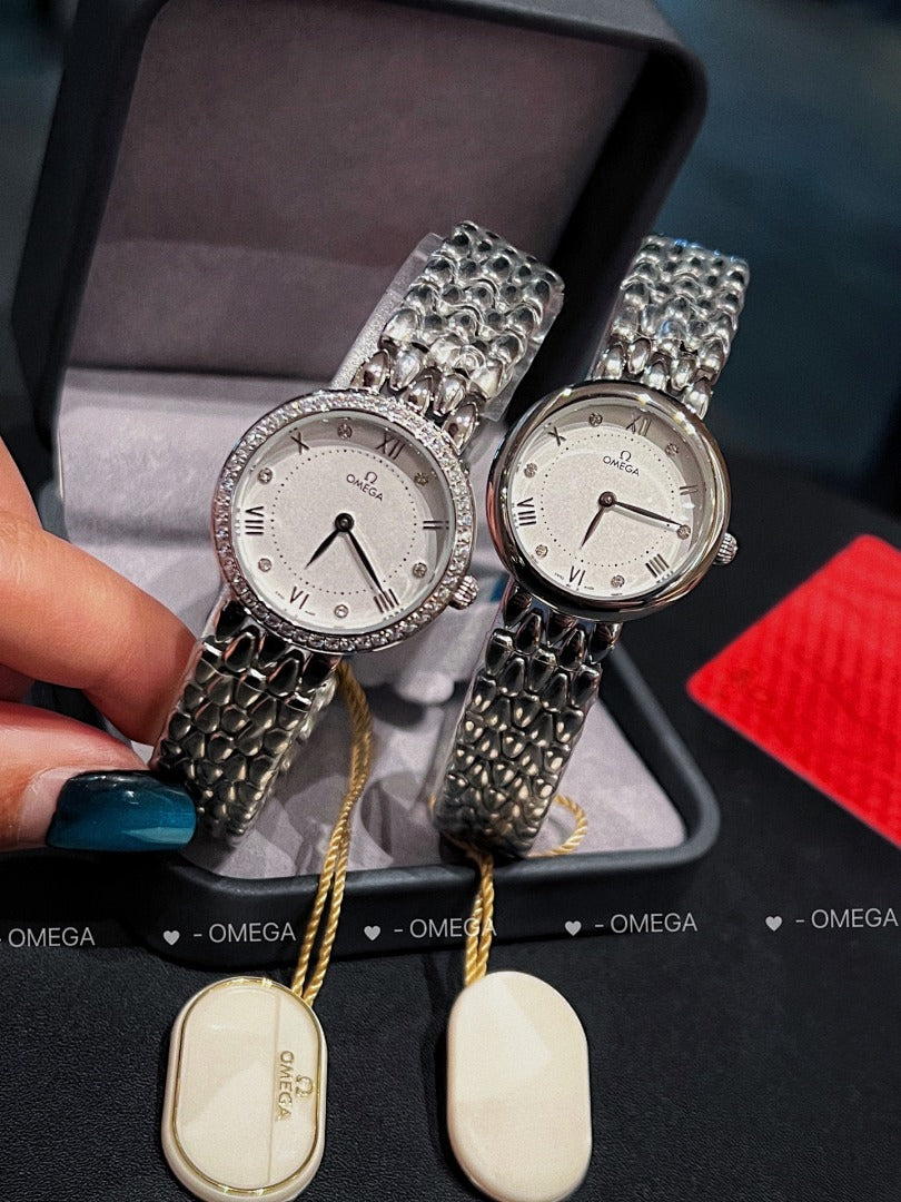 Omega watch pair with silver link bracelets, white dials, and round tag on yellow cord
