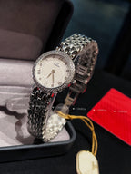Omega watch with silver link bracelet, white dial, and yellow cord with oval tag